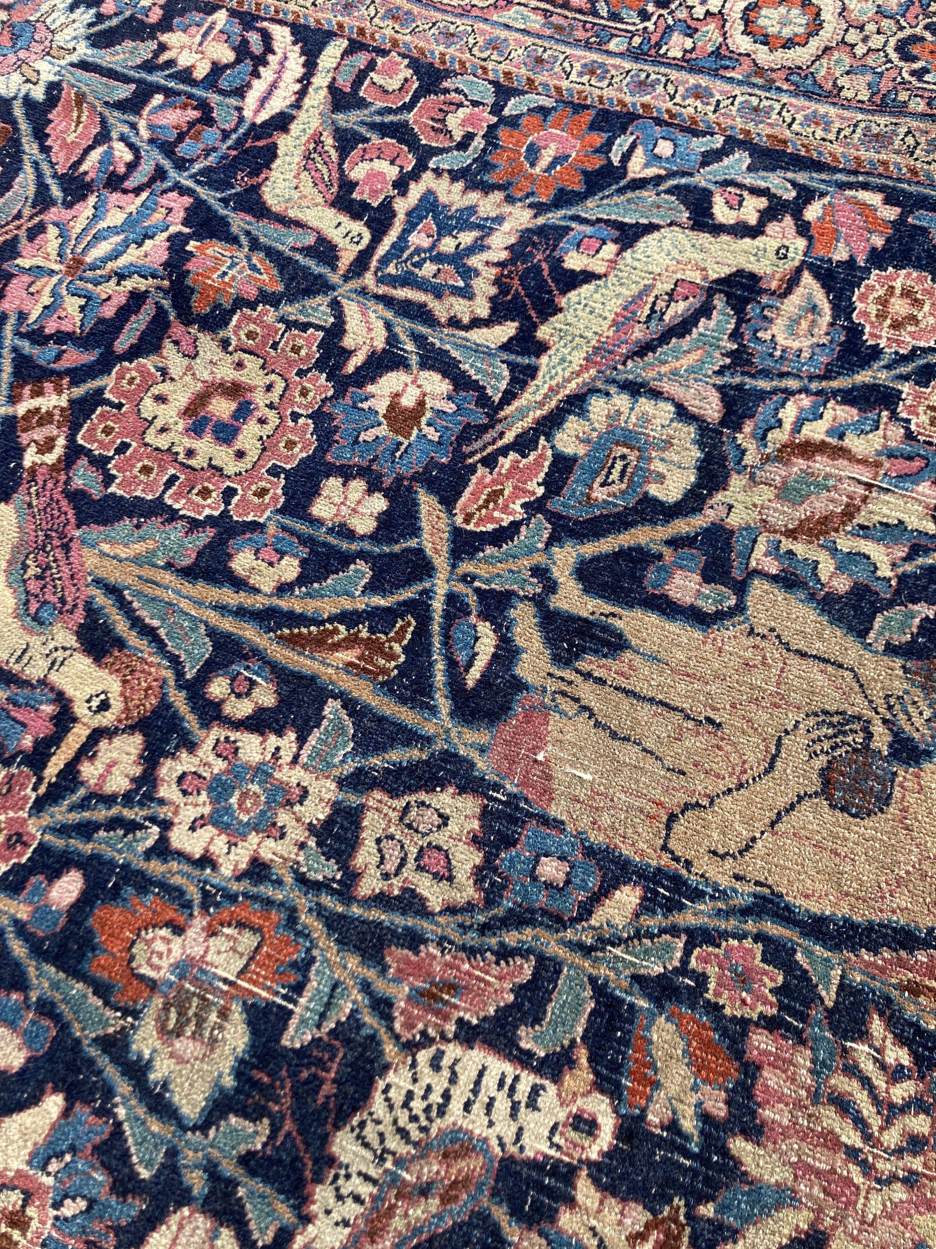 A Persian rug with a central Tree of Life interspersed with animals to include a seated monkey within the tree, a recumbent lion at the base, set within floral borders, 201 x 120cm